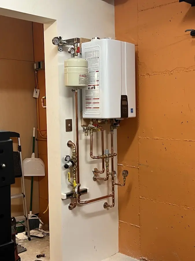 Plumbing technician inspecting water heater connections in Green